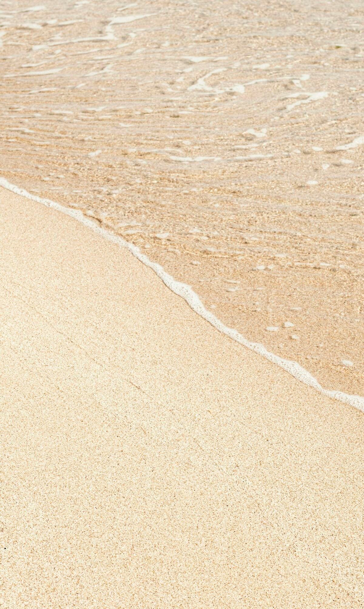 Soft sand and gentle waves on a sunlit beach